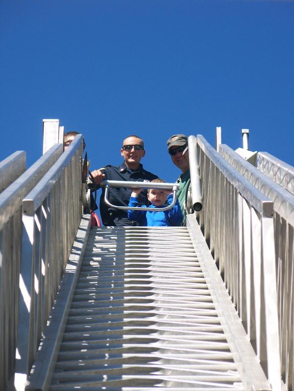 EMT Daniel Eldridge stands behind Robbie Slack who peers down from inside the ladder truck's bucket. BY MATTHEW BERNAT